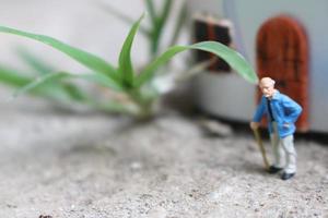 miniatura figura di un' nonno chi è in attesa nel davanti di il Casa. foto