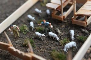 un' vicino su di miniatura figura di un' capra Herder alimentazione nel un' di legno gabbia. pastore concetto. foto