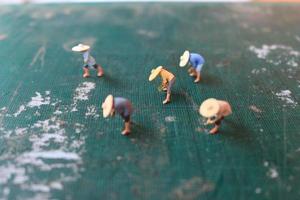 miniatura figure di agricoltori Lavorando su un' taglio stuoia. concetto di agricoltura foto. foto