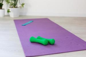 srotolato yoga stuoia su di legno pavimento nel moderno fitness centro o a casa con grande finestre e bianca mattone muri, confortevole spazio per fare sport esercizi, meditando, yoga attrezzatura foto