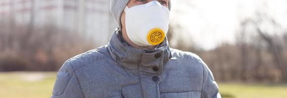 un' uomo indossare un' maschera su il strada. protezione contro virus e presa foto