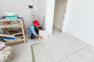 pavimento piastrella installazione, lavoratore nel un' bianca ufficio camera foto