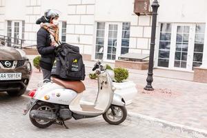 mascherato donna consegna cibo su un' motociclo foto