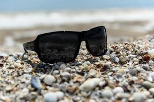 occhiali da sole in riva al mare foto