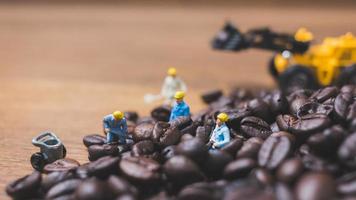 persone in miniatura che lavorano su chicchi di caffè tostati foto