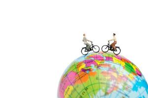 viaggiatori in miniatura con biciclette su un globo su uno sfondo bianco foto