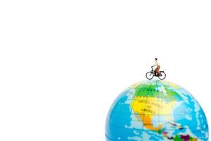 viaggiatore in miniatura con una bicicletta su un globo su uno sfondo bianco foto