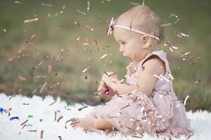 un' divertente poco ragazza nel un' luminosa coriandoli. bambino celebra uno anno. bellissimo bambino. foto