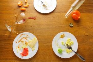 disordinato tavolo dopo festa. avanzi cibo, rovesciato bevande, sporco piatti. foto