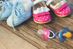 bambino scarpe e ciucci rosa e blu su il vecchio di legno sfondo. tonica Immagine. foto