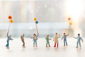 persone in miniatura che camminano con palloncini, concetto di famiglia felice foto