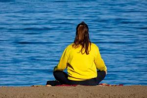 donna fare yoga su il riva del mare foto