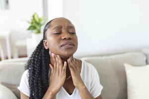 vicino su di giovane donna sfregamento sua infiammato tonsille, tonsillite problema, ritagliato. donna con tiroide ghiandola problema, toccante sua collo, ragazza ha un' dolorante gola foto