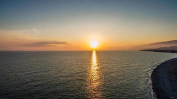 vista aerea del tramonto sul corpo d'acqua e sulle montagne foto