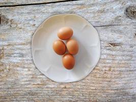 uova marroni su un piatto bianco su uno sfondo di tavolo in legno