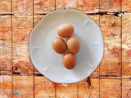 uova marroni su un piatto bianco su uno sfondo di tavolo in legno
