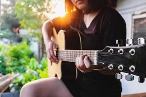 donna che suona una chitarra acustica foto