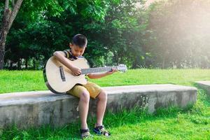 ragazzo che suona una chitarra in un giardino foto