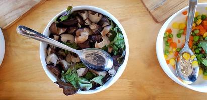 piatto posare di ciotola di fungo con affettato verde fagiolo, carota e Mais con inossidabile acciaio cucchiaio su di legno tavolo per prima colazione nel il mattina. salutare mangiare vita stile, verdura e dieta cibo concetto foto