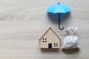 modello di casa una casa modello e un ombrello su uno sfondo di legno, assicurazione finanziaria e concetto di investimento sicuro foto