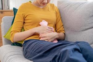 mestruazioni, periodo ciclo di mensile, male asiatico giovane donna, femmina mano nel mal di stomaco, soffrire a partire dal premestruale, pancia o addome dolore, utilizzando caldo acqua bottiglia. Salute problema infiammazione nel corpo. foto