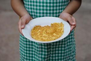 avvicinamento giovane ragazzo detiene piatto di frittata per prima colazione. presente il suo cucinando. concetto, facile delizioso cucinando menù. foto