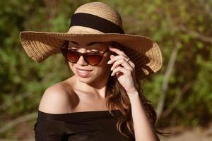 giovane donna nel cannuccia cappello avvicinamento nel occhiali da sole foto