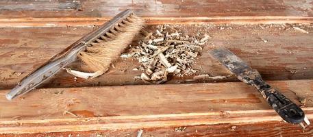 spatola e pennello con trucioli di legno rotti su un tavolo di legno foto