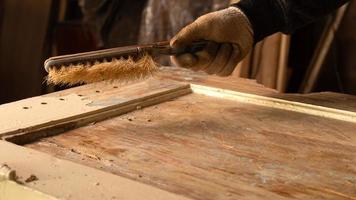 mani che puliscono vecchia vernice da una porta di legno, restauro di mobili in legno
