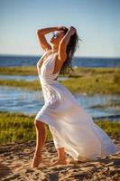 bellissimo donna nel bianca vestito in posa su il riva