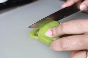 vicino su di taglio Kiwi frutta con un' coltello foto