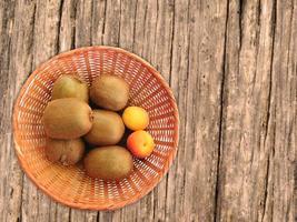 kiwi e albicocche in un cesto di vimini su uno sfondo di tavolo in legno