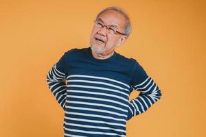 asiatico anziano uomo sensazione mal di schiena o indietro dolore su il giallo sfondo. foto