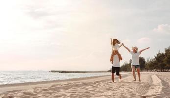 contento asiatico famiglia godere il mare spiaggia a consistente padre, madre e figlia avendo divertimento giocando spiaggia nel estate vacanza su il oceano spiaggia. contento famiglia con vacanze tempo stile di vita concetto. foto