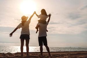 contento asiatico famiglia godere il mare spiaggia a consistente padre, madre e figlia avendo divertimento giocando spiaggia nel estate vacanza su il oceano spiaggia. contento famiglia con vacanze tempo stile di vita concetto. foto