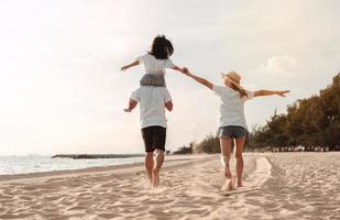 contento asiatico famiglia godere il mare spiaggia a consistente padre, madre e figlia avendo divertimento giocando spiaggia nel estate vacanza su il oceano spiaggia. contento famiglia con vacanze tempo stile di vita concetto. foto