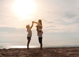 contento asiatico famiglia godere il mare spiaggia a consistente padre, madre e figlia avendo divertimento giocando spiaggia nel estate vacanza su il oceano spiaggia. contento famiglia con vacanze tempo stile di vita concetto. foto