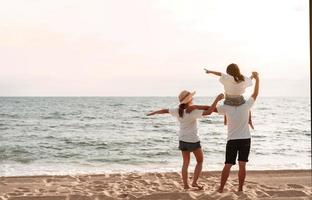 contento asiatico famiglia godere il mare spiaggia a consistente padre, madre e figlia avendo divertimento giocando spiaggia nel estate vacanza su il oceano spiaggia. contento famiglia con vacanze tempo stile di vita concetto. foto