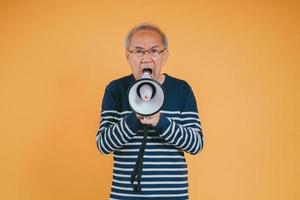 anziano maschio urlando con megafono per annunciare notizia o sconto vendita shopping su colore sfondo. foto