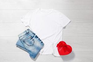 bianca maglietta modello. san valentino giorno concetto camicia, regalo scatola cuore forma su di legno sfondo. copia spazio, modello vuoto davanti Visualizza maglietta Abiti. romantico vestito. piatto posare vacanza moda foto