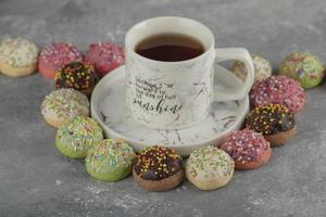 ciambelle dolci colorate con codette e una tazza di tè