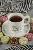 ciambelle dolci colorate con codette e una tazza di tè