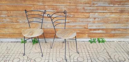 Due vecchio sedie mettendo su titolo pavimento con vecchio grunge Marrone di legno parete sfondo con copia spazio. mobilia e Vintage ▾ o retrò oggetto. foto