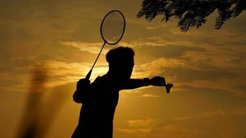 sagome uomo è Tenere il volano e il badminton racchetta foto