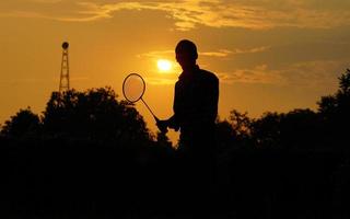 sagome uomo è Tenere il volano e il badminton racchetta foto