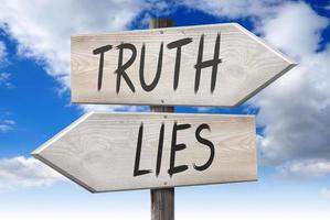bugie, verità - di legno cartello stradale con Due frecce e nuvoloso cielo nel sfondo foto