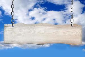 vuoto di legno tavola sospeso su Catene con nuvoloso cielo nel sfondo foto