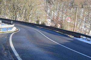 nazione strada curve con neve nel il foresta foto