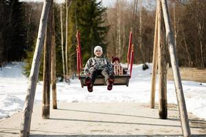 più vecchio fratello con minore sorella oscillante su grande di legno swing nel foresta di montagne. foto