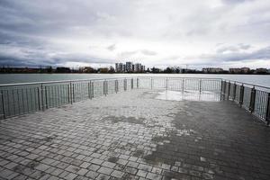 molo di lago lungomare con bicchiere edificio multipiano residenziale Casa su sfondo. foto